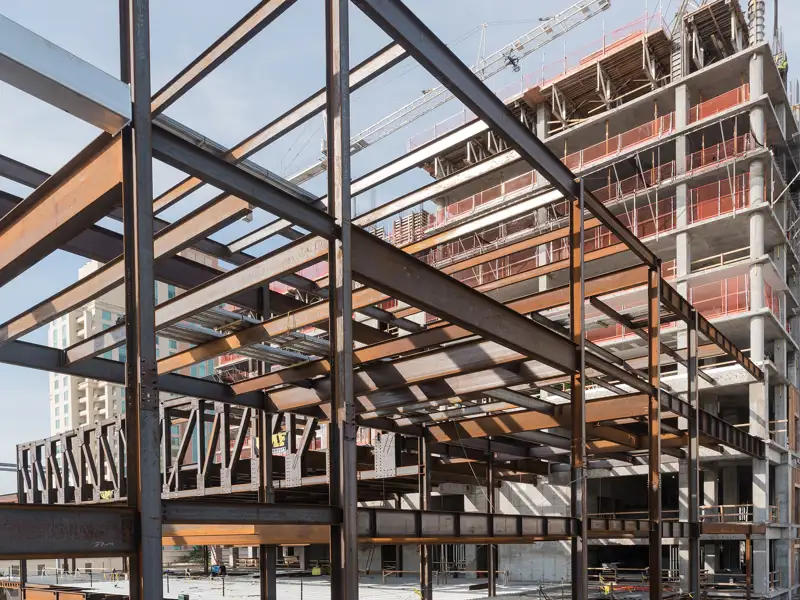 A grid of steel beams frame a large building under construction.