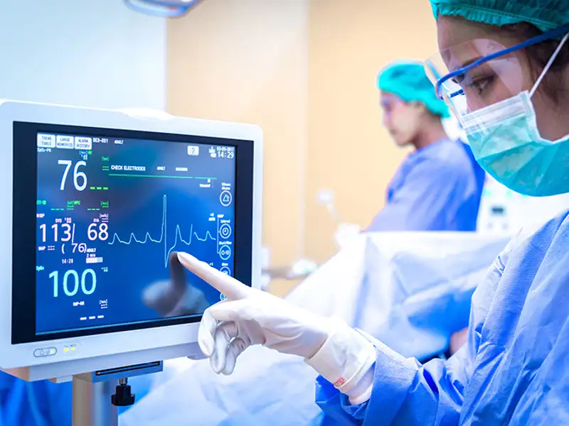 Medical professionals review a patient's vital statistics on a monitor.