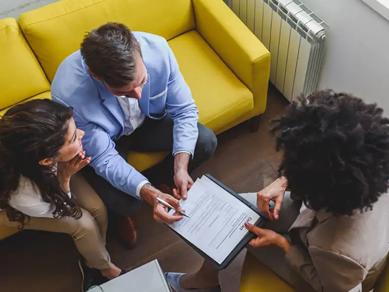 Overhead view of a couple reviewing insurance forms with an agent.